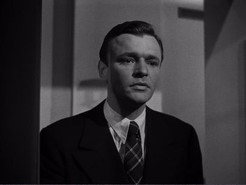 Movie still from “Address Unknown” (1944), directed by William Cameron Menzies – Black and white photograph of a man wearing a suit and tie; Close Up shot, Low angle