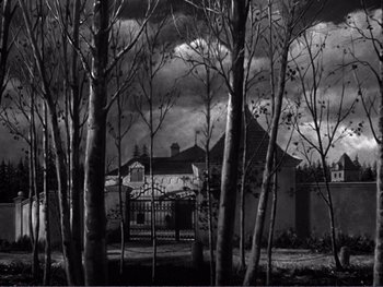 Movie still from “Address Unknown” (1944), directed by William Cameron Menzies – A black - and - white photo of a house and trees; Extreme Wide shot, Low angle