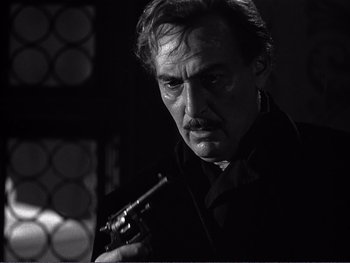 Movie still from “Address Unknown” (1944), directed by William Cameron Menzies – Black and white photograph of a man holding a gun; Close Up shot, Low angle