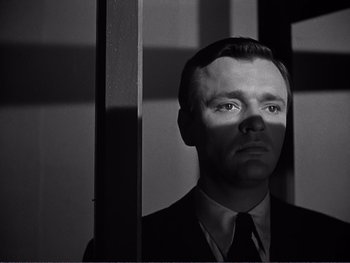 Movie still from “Address Unknown” (1944), directed by William Cameron Menzies – A black and white photo of a man in a suit and tie; Close Up shot, Low angle