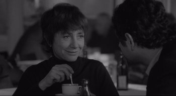 A woman sitting at a table with a cup of coffee