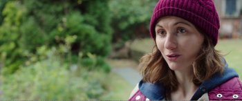 Movie still from “Adult Life Skills” (2016), directed by Rachel Tunnard – A person wearing a hat with trees in the background; Close Up shot, Over the shoulder angle