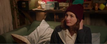 Movie still from “Adult Life Skills” (2016), directed by Rachel Tunnard – A woman sitting on a couch in a living room; Medium shot, Over the shoulder angle