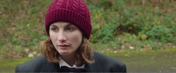 Movie still from “Adult Life Skills” (2016), directed by Rachel Tunnard – A woman wearing a red hat and a bow tie; Close Up shot, Over the shoulder angle