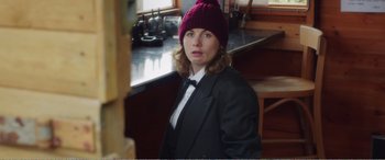 Movie still from “Adult Life Skills” (2016), directed by Rachel Tunnard – A woman wearing a black suit and a pink hat; Medium shot, Over the shoulder angle