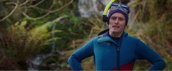 Movie still from “Adult Life Skills” (2016), directed by Rachel Tunnard – A man in a blue and black jacket and a yellow hat; Medium shot, Over the shoulder angle