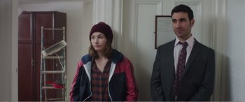 Movie still from “Adult Life Skills” (2016), directed by Rachel Tunnard – A woman and a man standing next to each other in a room; Medium shot, Over the shoulder angle