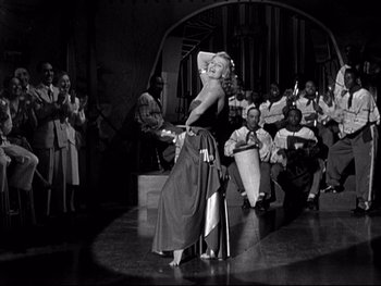 Movie still from “Affair in Trinidad” (1952), directed by Vincent Sherman – A woman in a black and white photo is dancing; Wide shot, Low angle