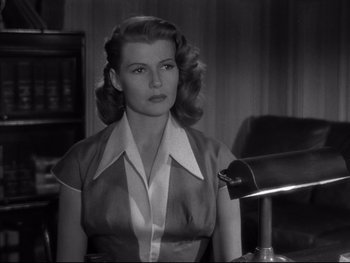 Movie still from “Affair in Trinidad” (1952), directed by Vincent Sherman – A black - and - white photo of a woman in an office setting; Close Up shot, Low angle