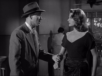 Movie still from “Affair in Trinidad” (1952), directed by Vincent Sherman – A man and a woman shaking hands in a black and white photo; Medium shot, Over the shoulder angle