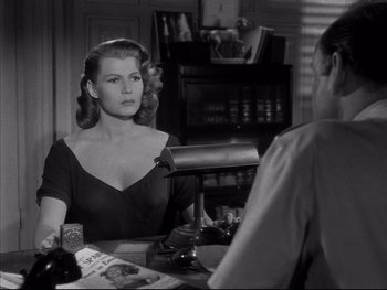 Movie still from “Affair in Trinidad” (1952), directed by Vincent Sherman – A black and white photo of a woman sitting at a table with a man; Medium shot, Over the shoulder angle