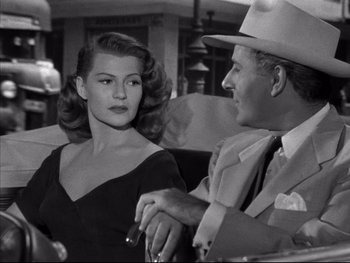 Movie still from “Affair in Trinidad” (1952), directed by Vincent Sherman – A man and a woman sitting at a table in front of each other; Medium shot, Low angle