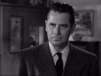 Movie still from “Affair in Trinidad” (1952), directed by Vincent Sherman – Black and white photograph of a man in a suit; Close Up shot, Low angle