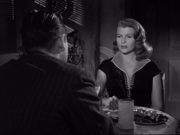 Movie still from “Affair in Trinidad” (1952), directed by Vincent Sherman – A man and a woman sitting at a dinner table; Medium shot, Over the shoulder angle