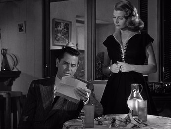 Movie still from “Affair in Trinidad” (1952), directed by Vincent Sherman – A man sitting at a dinner table with a woman; Medium shot, Low angle