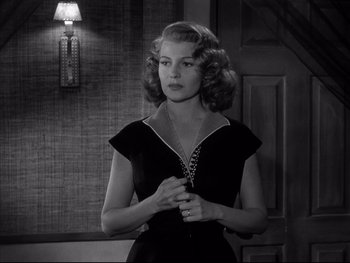 Movie still from “Affair in Trinidad” (1952), directed by Vincent Sherman – A black and white photo of a woman holding a necklace; Medium shot, Over the shoulder angle