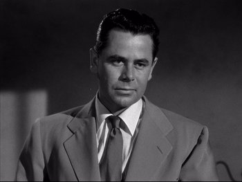Movie still from “Affair in Trinidad” (1952), directed by Vincent Sherman – Black and white photograph of a man wearing a suit and tie; Close Up shot, Low angle