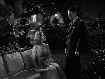 Movie still from “Affair in Trinidad” (1952), directed by Vincent Sherman – A man and a woman sitting on a couch outside at night; Medium shot, High angle