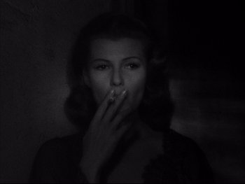 Movie still from “Affair in Trinidad” (1952), directed by Vincent Sherman – A black and white photo of a woman smoking a cigarette; Close Up shot, Low angle