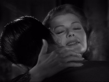 Movie still from “Affair in Trinidad” (1952), directed by Vincent Sherman – A woman is being hugged by another woman in a black and white photo; Close Up shot, Low angle