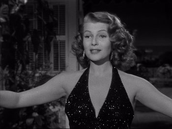 Movie still from “Affair in Trinidad” (1952), directed by Vincent Sherman – A woman in a black dress is posing for a picture; Close Up shot, Low angle