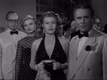 Movie still from “Affair in Trinidad” (1952), directed by Vincent Sherman – A group of people standing next to each other in a room; Medium shot, Low angle