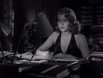 Movie still from “Affair in Trinidad” (1952), directed by Vincent Sherman – A woman sitting in front of a computer desk; Medium shot, High angle