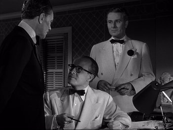 Movie still from “Affair in Trinidad” (1952), directed by Vincent Sherman – A man in a suit and tie talking to another man in a suit and tie; Medium shot, Over the shoulder angle