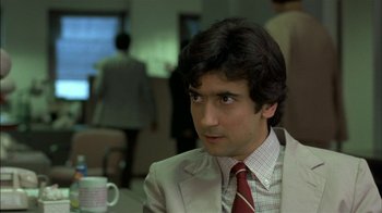 Movie still from “After Hours” (1985), directed by Martin Scorsese – A man in a suit and tie sitting at a table with a coffee mug; Close Up shot, Over the shoulder angle
