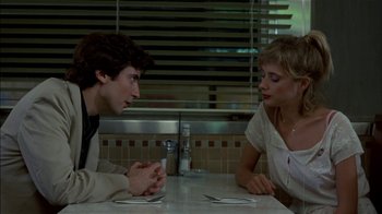 Movie still from “After Hours” (1985), directed by Martin Scorsese – A man and a woman sitting at a table talking to each other; Medium shot, Over the shoulder angle