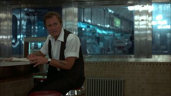 Movie still from “After Hours” (1985), directed by Martin Scorsese – A man sitting at a table in a restaurant; Medium shot, Over the shoulder angle