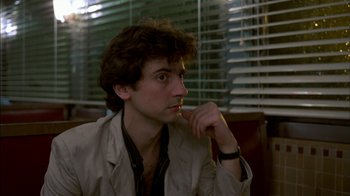 Movie still from “After Hours” (1985), directed by Martin Scorsese – A young man sitting in front of a window with his hand under his chin; Close Up shot, Low angle