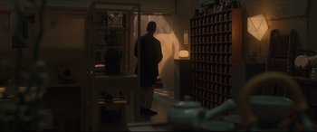 Movie still from “After Yang” (2021), directed by Kogonada – A man standing in a room with a lot of shelves; Wide shot, Over the shoulder angle