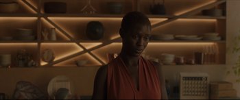 Movie still from “After Yang” (2021), directed by Kogonada – A woman in a red dress is looking to her left; Close Up shot, Over the shoulder angle