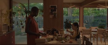 Movie still from “After Yang” (2021), directed by Kogonada – Two people sitting at a table with food on it; Medium shot, Over the shoulder angle