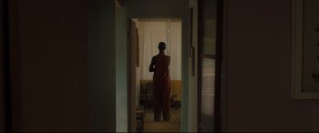Movie still from “After Yang” (2021), directed by Kogonada – A person standing in a room looking out a window; Wide shot, Low angle