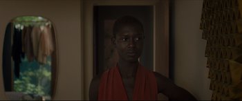 Movie still from “After Yang” (2021), directed by Kogonada – A woman in a red shirt is standing in a room; Close Up shot, Over the shoulder angle