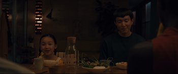 Movie still from “After Yang” (2021), directed by Kogonada – Two people sitting at a table with a bowl of food; Medium shot, Over the shoulder angle