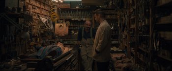 Movie still from “After Yang” (2021), directed by Kogonada – Two men standing in a shop talking to each other; Wide shot, Over the shoulder angle