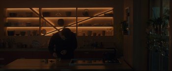 Movie still from “After Yang” (2021), directed by Kogonada – A person standing at a counter in front of a shelf; Wide shot, Low angle