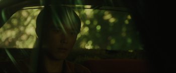 Movie still from “After Yang” (2021), directed by Kogonada – A young man sitting in a car looking out the window; Close Up shot, Low angle