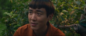 Movie still from “After Yang” (2021), directed by Kogonada – A person wearing a red shirt; Close Up shot, High angle