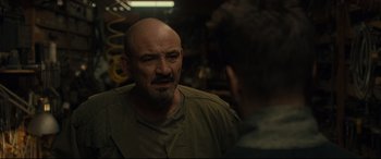 Movie still from “After Yang” (2021), directed by Kogonada – A man with a shaved head talking to another man in front of him; Close Up shot, Over the shoulder angle