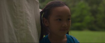 Movie still from “After Yang” (2021), directed by Kogonada – A little girl with a pony tail is smiling; Close Up shot, Over the shoulder angle