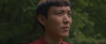 Movie still from “After Yang” (2021), directed by Kogonada – A person wearing a red shirt; Close Up shot, High angle