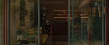 Movie still from “After Yang” (2021), directed by Kogonada – A view of a living room through a glass door; Wide shot, Low angle