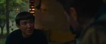 Movie still from “After Yang” (2021), directed by Kogonada – Two men are sitting in a room and one of them is talking to another man; Close Up shot, Over the shoulder angle