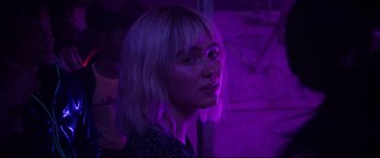Movie still from “After Yang” (2021), directed by Kogonada – A woman with blonde hair is standing in front of a purple light; Close Up shot, Over the shoulder angle