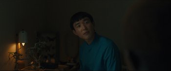 Movie still from “After Yang” (2021), directed by Kogonada – A man in a blue shirt is in the dark; Close Up shot, Over the shoulder angle