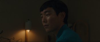 Movie still from “After Yang” (2021), directed by Kogonada – A man with a blue shirt is looking at the camera; Close Up shot, Over the shoulder angle